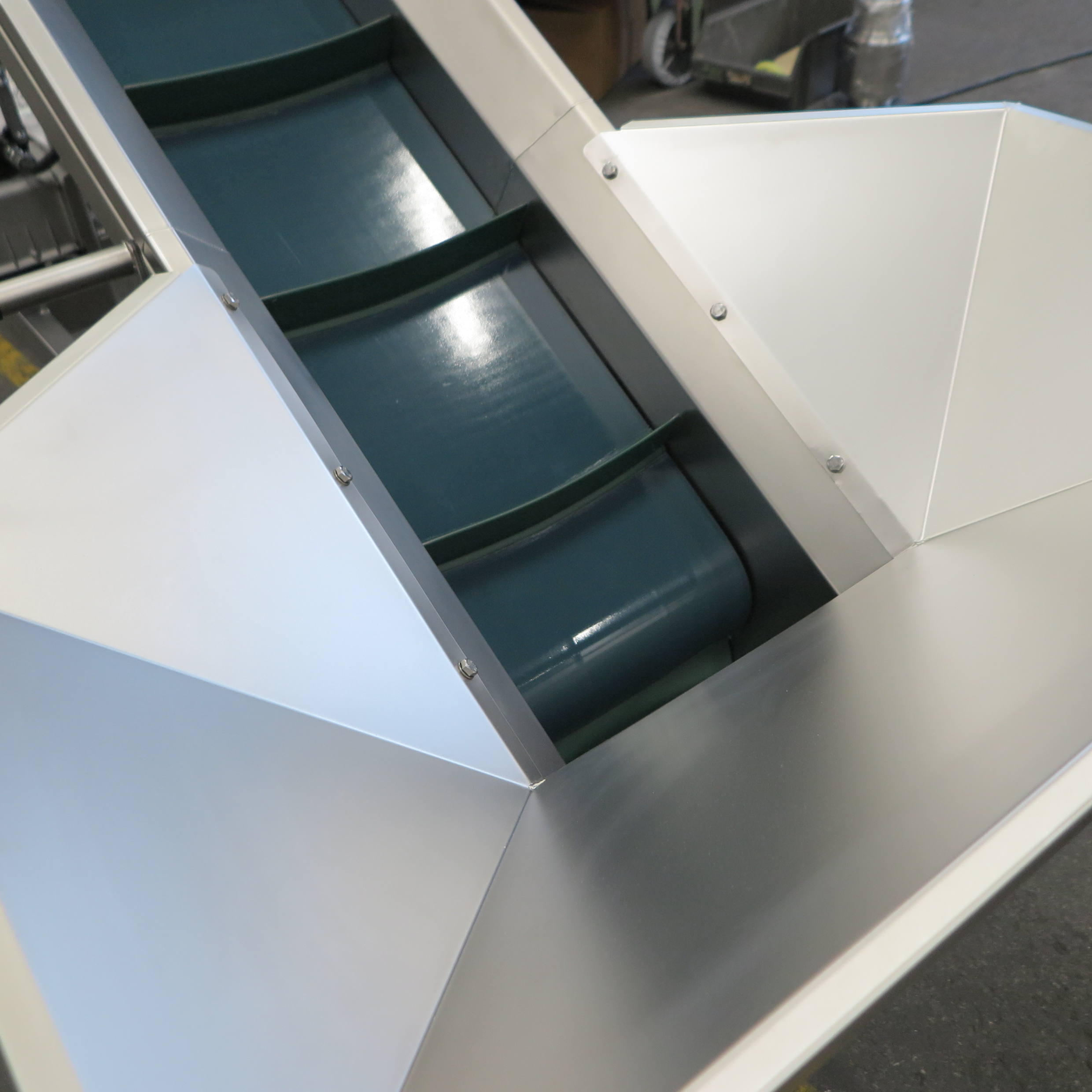 Nastro elevatore. Telaio autoportante in acciaio inox EN 1.4301 su ruote girevoli. Inclinazione regolabile del nastro. Nastro in PVC alimentare con listelli curvi. Sistema di tensionamento e rilascio (sblocco) rapido. Ugelli integrati per il risciacquo del nastro. Vaschetta recupero liquidi con scarico.